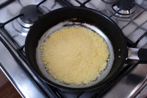 Mbejú cocinándose en una sartén sobre cocina a gas